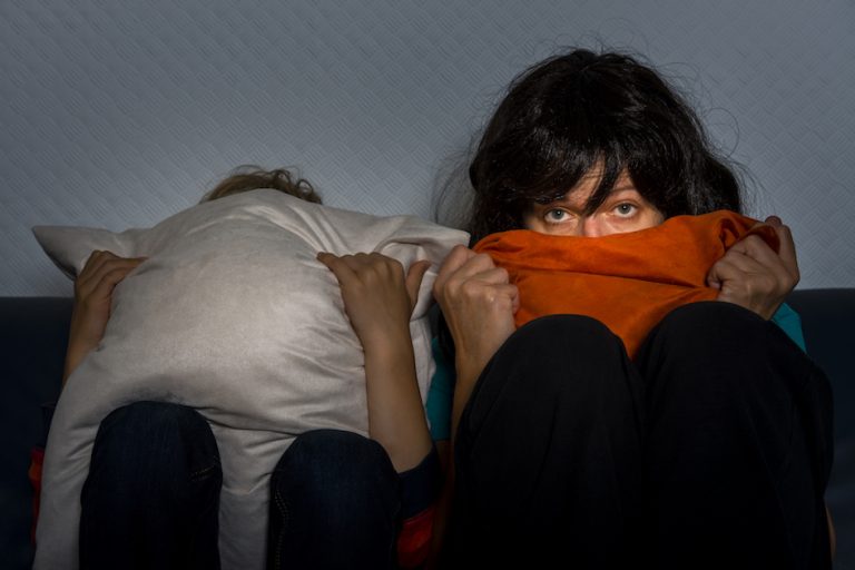 afraid mother and child watching television and hiding the faces